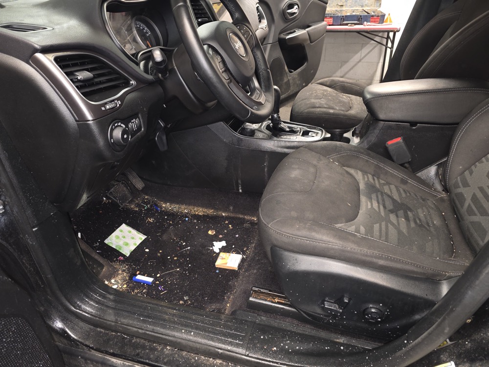 Heavily soiled Jeep interior before detailing — debris through the footwell